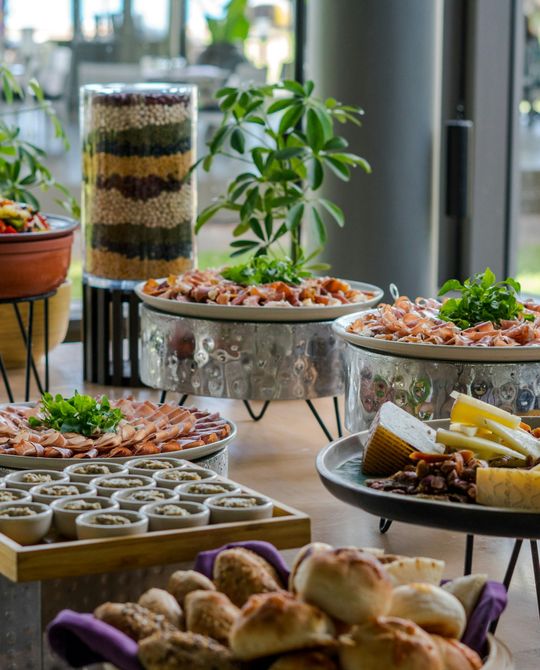 Mesa de buffet com pão, frios e sobremesas