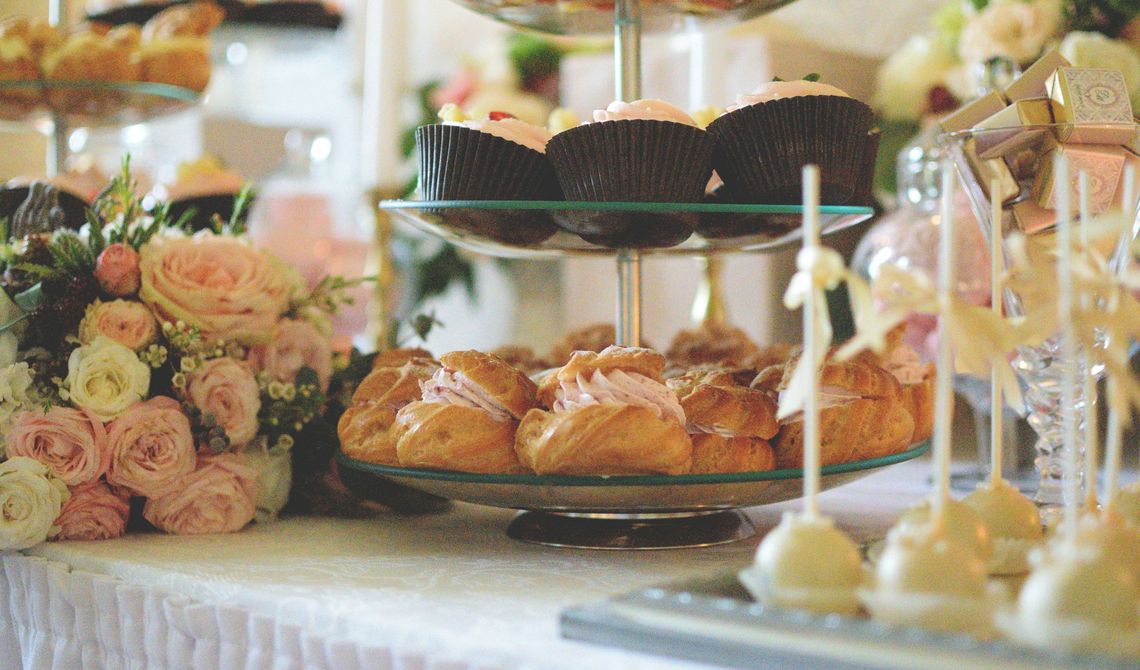 Mesa de sobremesas com bolinhos, pastéis e flores