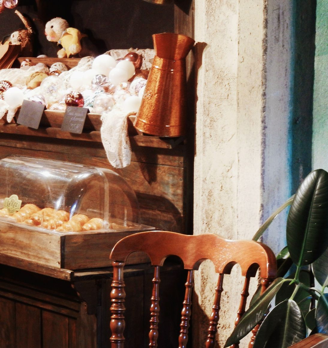 Vitrine de madeira com bolos e doces, ao lado de uma cadeira antiga