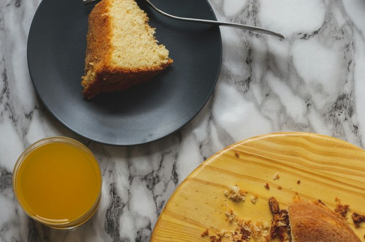 Fatia de bolo simples ao lado de um copo de sumo de laranja