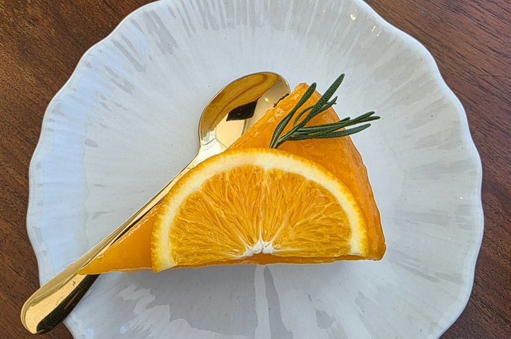 Fatia de bolo de laranja com rodela de laranja e alecrim