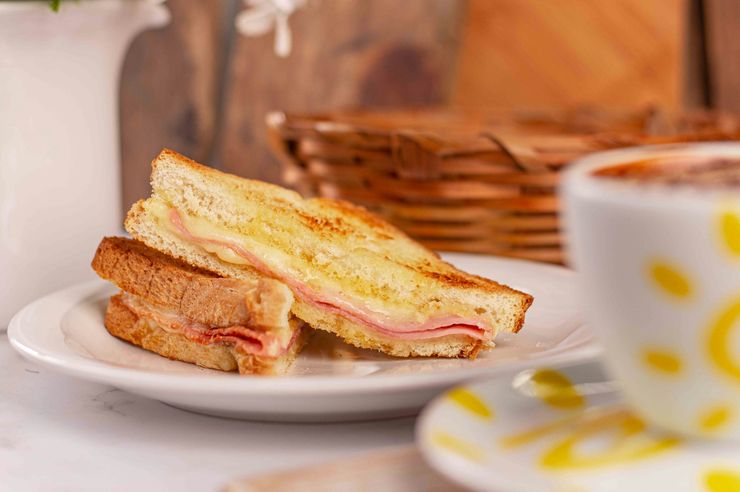 Tosta de fiambre e queijo ao lado de um café