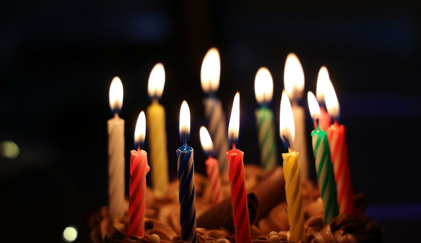 Velas coloridas acesas num bolo de aniversário