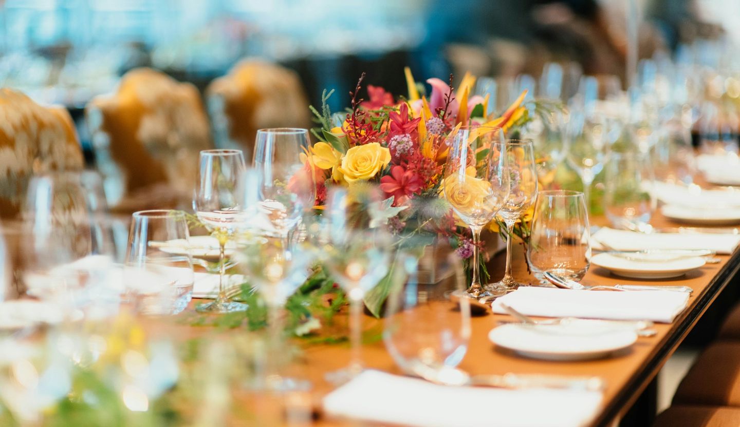 Mesa comprida de casamento com flores coloridas, copos e pratos