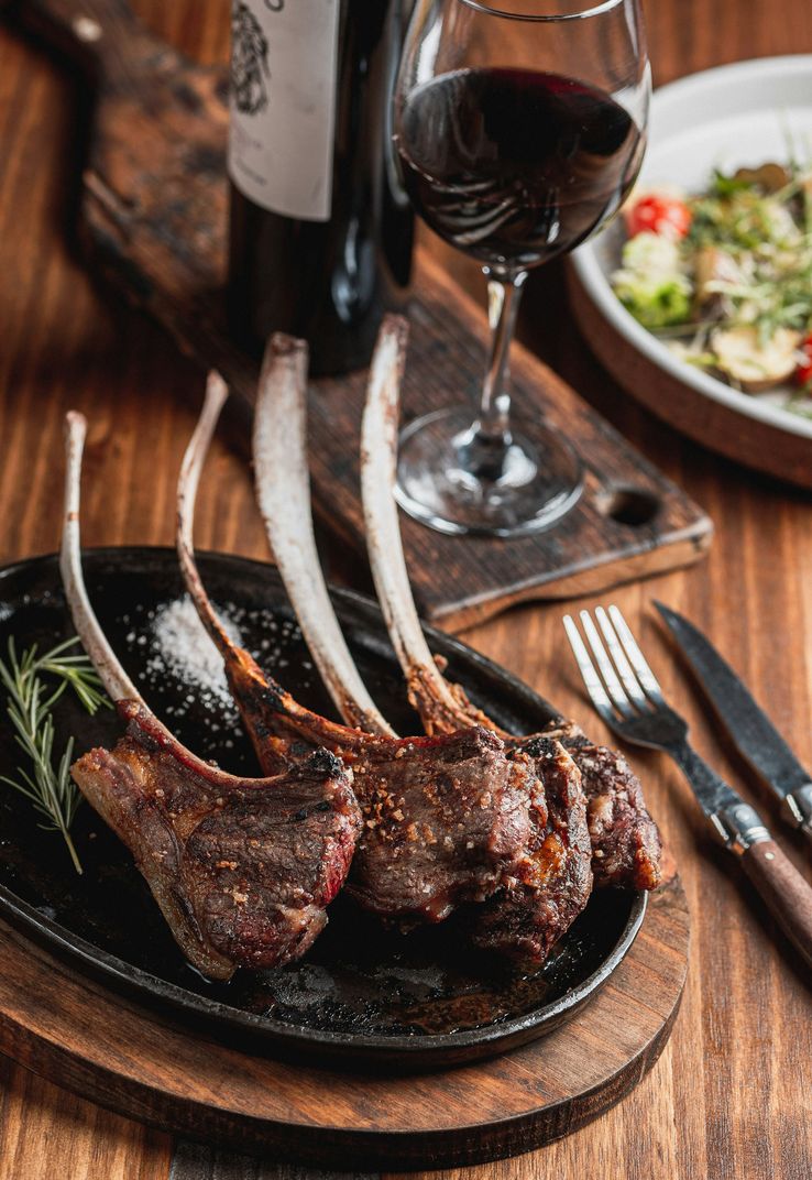 Costeletas de borrego grelhadas, servidas com vinho tinto