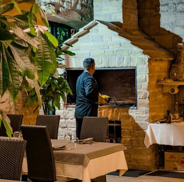 Cozinheiro junto a um grelhador de pedra, numa sala de refeições