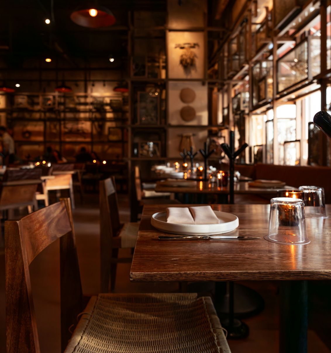 Sala de restaurante rústica, com mesas de madeira e luz quente